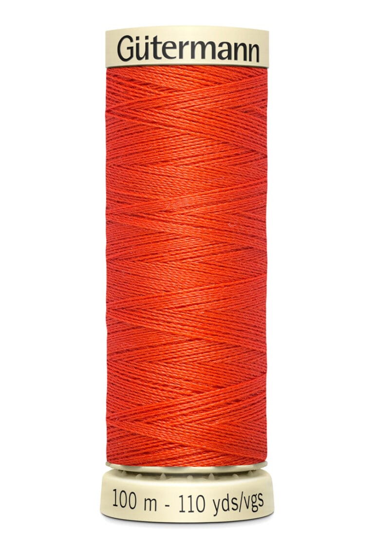 A spool of Gütermann red sewing thread, with cream-colored ends. The label indicates the length as 100 meters or 110 yards. The thread is tightly wound around the spool.