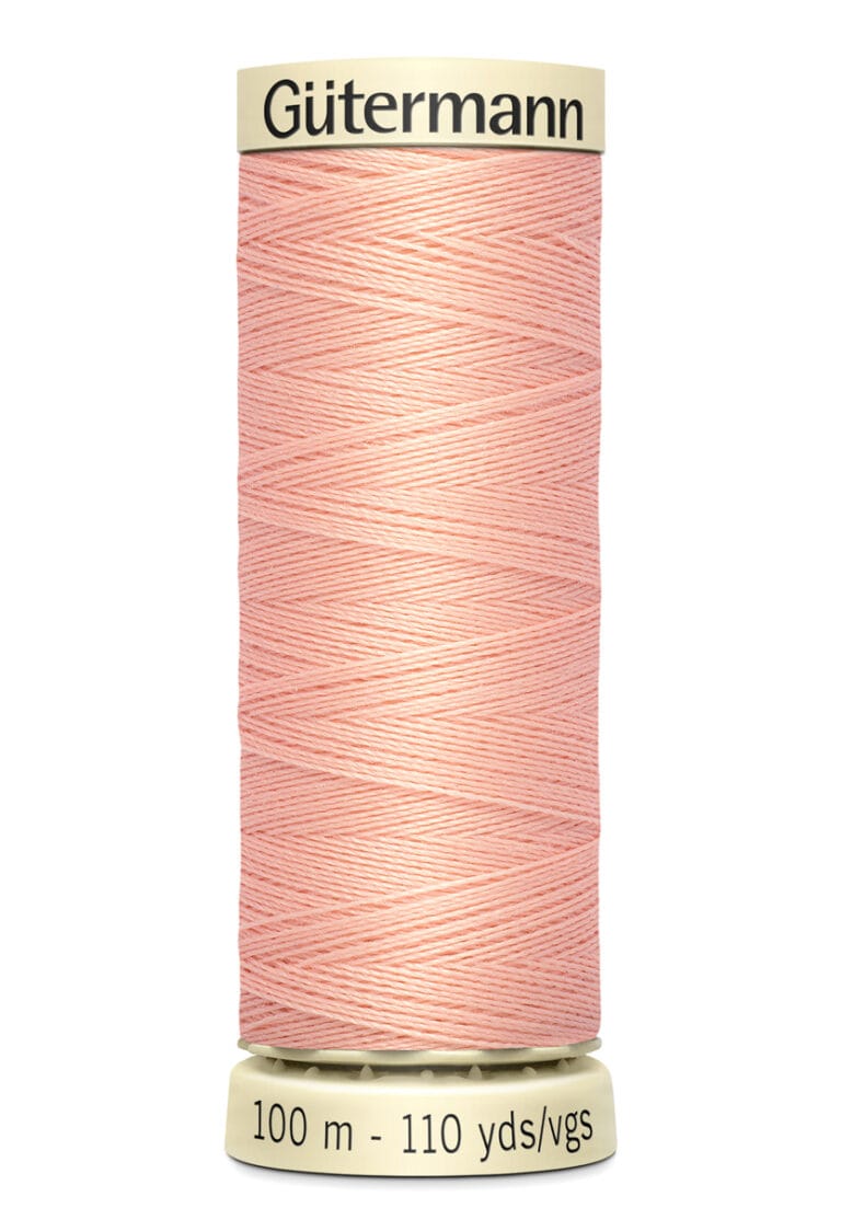 A spool of Gütermann thread in light pink, featuring a crisscross pattern. The base indicates the length as 100 meters or 110 yards.