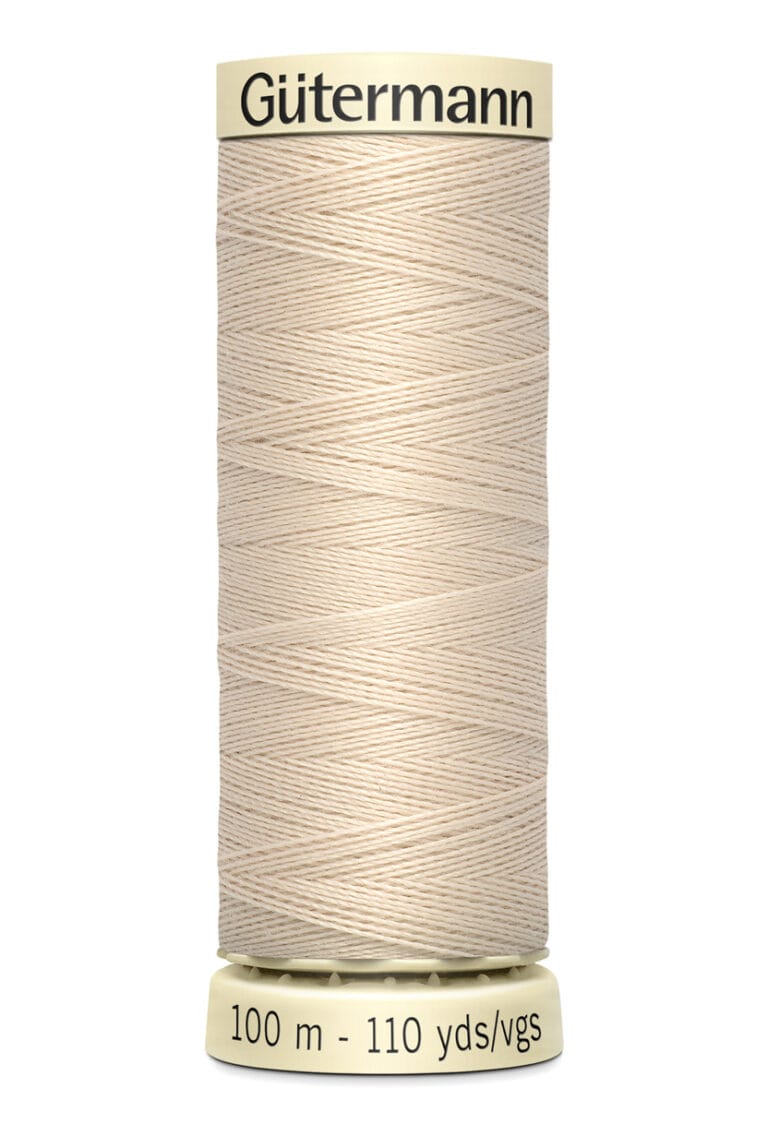 Spool of Gütermann sewing thread in beige, wrapped tightly around a cylindrical cream-colored spool. Labeled with "Gütermann" and "100 m - 110 yds/vgs.