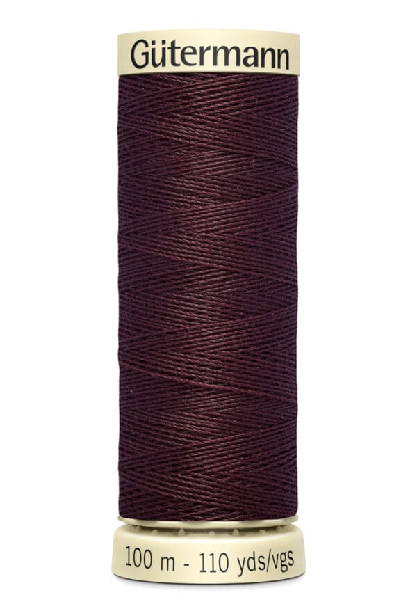 A spool of Gütermann thread in deep burgundy color. The label on the spool reads "100 m - 110 yds/vgs." The thread is tightly wound around the cylindrical spool, with a beige top and base.