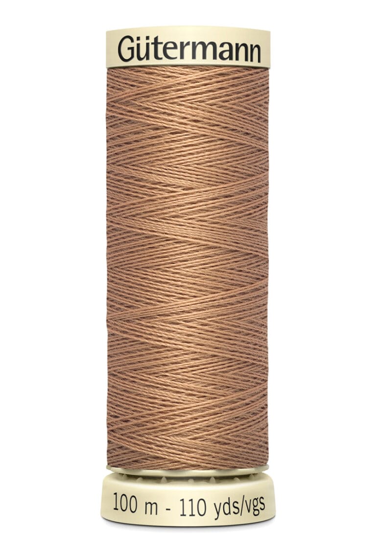 A spool of Gütermann brown thread, labeled with "100 m - 110 yds/vgs" on the base. The thread is neatly wound around the cylindrical spool, in a light beige tone.