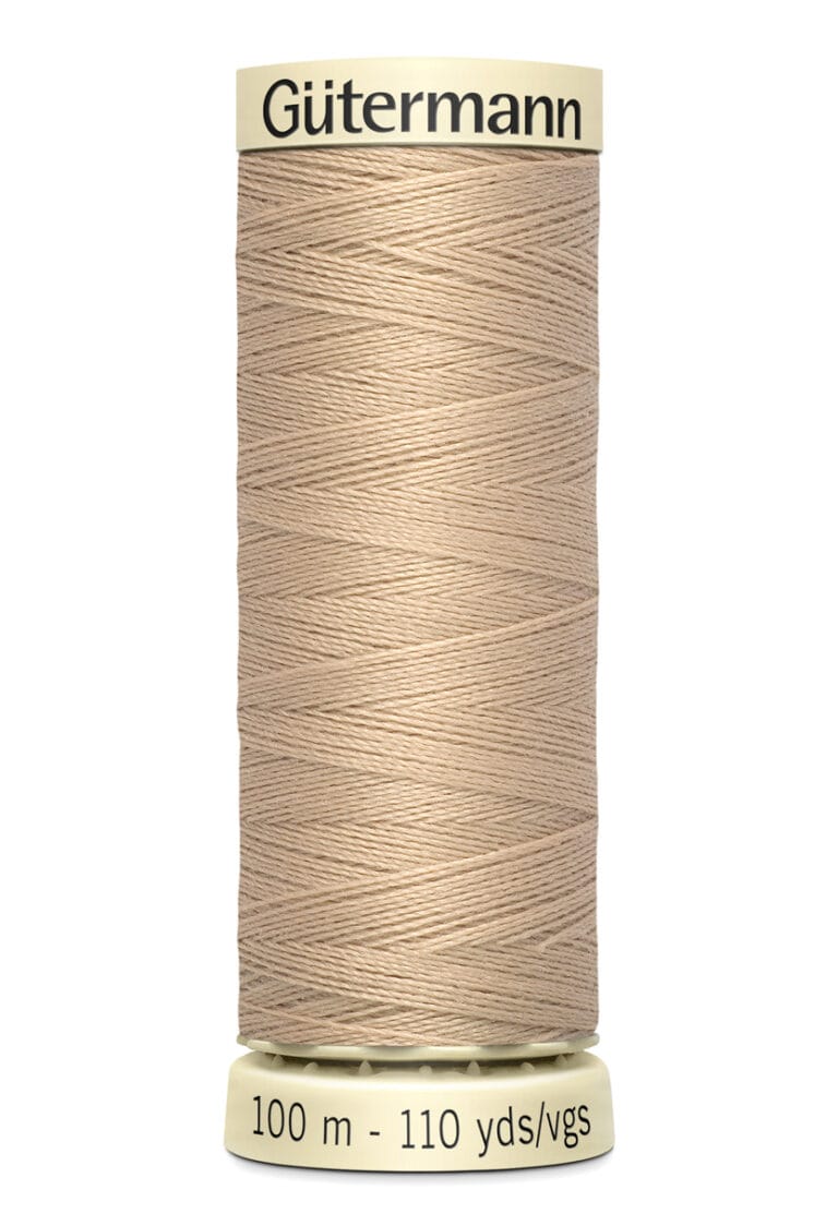 A spool of Gütermann thread in light beige, wound neatly, with labels showing "100 m - 110 yds/vgs.