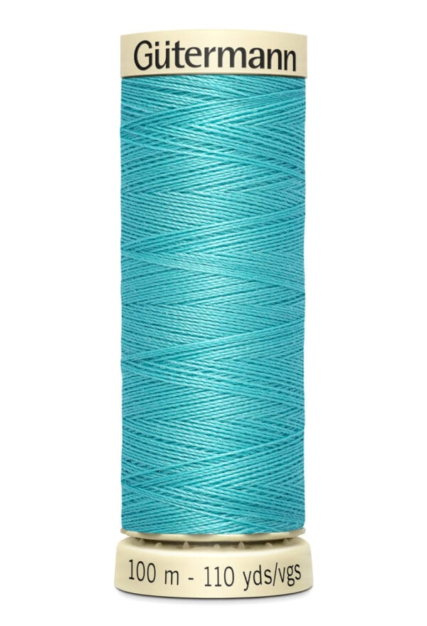 A spool of Gütermann thread with a turquoise color. The label indicates 100 meters or 110 yards. The spool is cylindrical with a beige base and top.