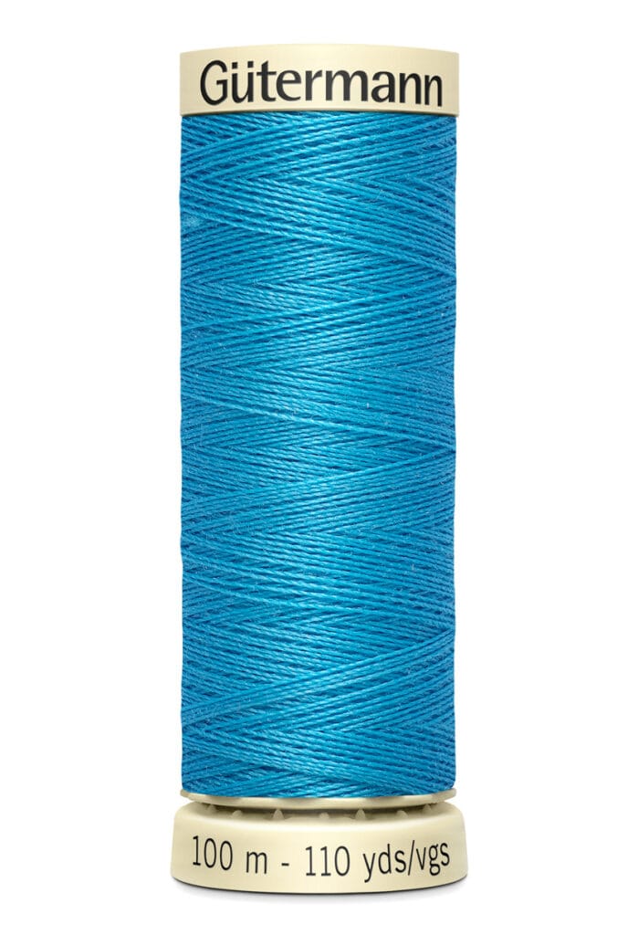 A spool of Gütermann thread in bright blue, labeled with "100 m - 110 yds/vgs" on the light-colored top and base. The thread is neatly wound in distinct layers, showing its texture and vibrancy.