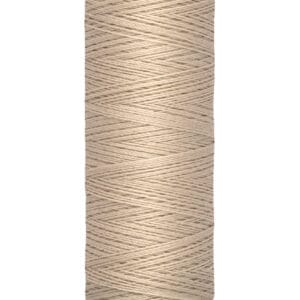 A spool of Gutermann thread in a beige color, with labeling that reads "100 m - 110 yds/vgs" on the base. The thread is wound neatly around a cream-colored cylindrical holder.