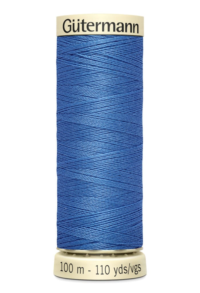 A spool of Gütermann sewing thread in blue, labeled "100 m - 110 yds/vgs." The spool is cream-colored with the brand name printed on the top.