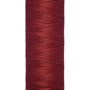 A spool of Gütermann thread in dark red, containing 100 meters or 110 yards of thread. The spool is cylindrical with light beige ends, and the thread is neatly wound around it.
