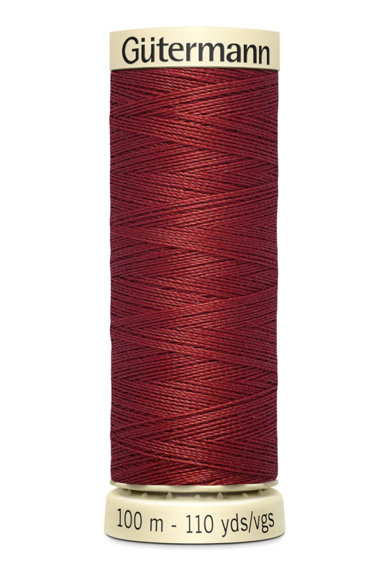 A spool of Gütermann thread in dark red, containing 100 meters or 110 yards of thread. The spool is cylindrical with light beige ends, and the thread is neatly wound around it.