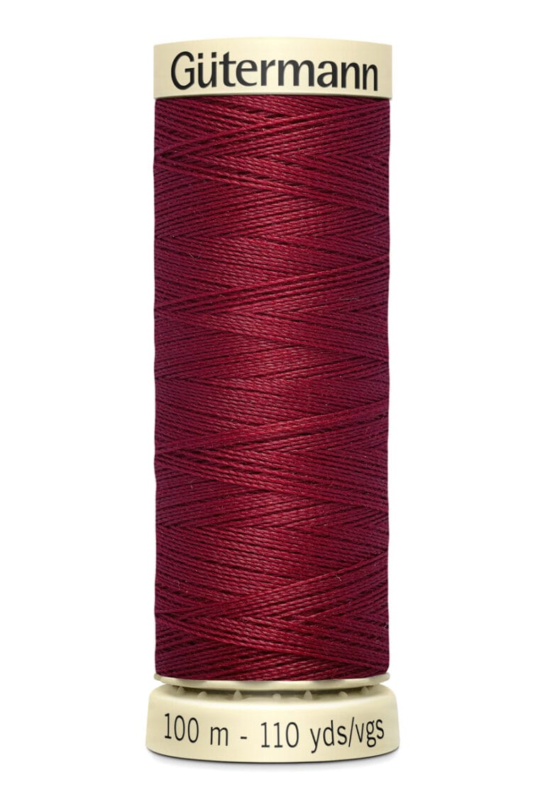 A spool of Gütermann thread, filled with deep red thread. The label indicates a length of 100 meters or 110 yards. The spool is cream-colored with black text.