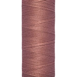 A spool of Gütermann thread in a dusty rose color is shown. The label indicates the length as 100 meters, or 110 yards. The spool is cylindrical with a beige top and bottom.