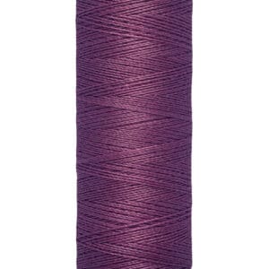 A spool of purple Gütermann thread, labeled with "100 m - 110 yds," stands upright with beige caps on top and bottom.