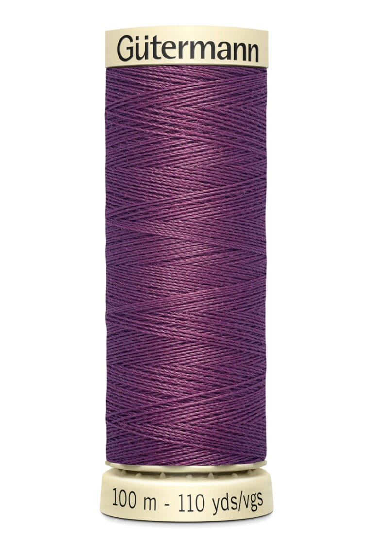 A spool of purple Gütermann thread, labeled with "100 m - 110 yds," stands upright with beige caps on top and bottom.