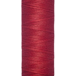 A spool of Gütermann red sewing thread, showing fine texture. The spool is labeled with "100 m - 110 yds/vgs.