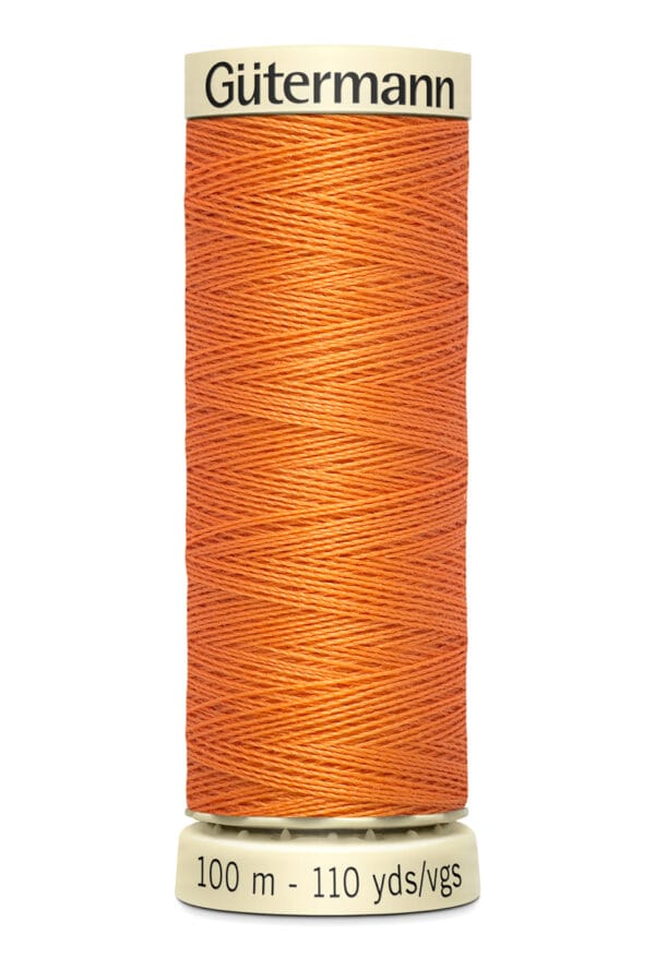 A spool of Gütermann thread in bright orange. The label indicates it contains 100 meters or 110 yards of thread. The spool is cylindrical with thread neatly wound around it.