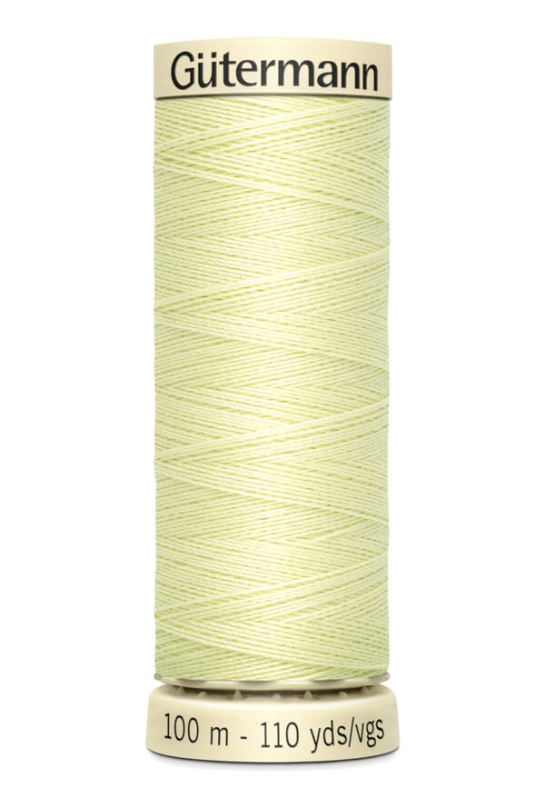 A spool of Gütermann sewing thread, pale yellow in color, stands upright. The label reads "100 m - 110 yds/vgs." The spool's top and bottom are beige.