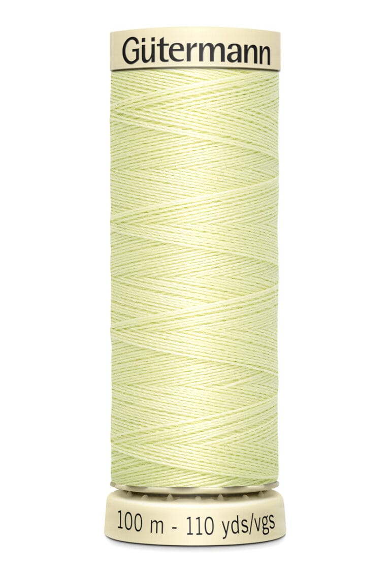 A spool of Gütermann sewing thread, pale yellow in color, stands upright. The label reads "100 m - 110 yds/vgs." The spool's top and bottom are beige.