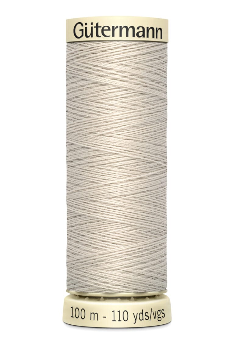 A spool of Gütermann thread in light beige, labeled with 100 meters and 110 yards. The spool is designed with narrow grooves to hold the thread securely.