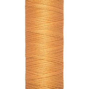 A spool of Gütermann thread in a light brown color, with labels indicating 100 meters and 110 yards. The thread is neatly wound around a beige spool.