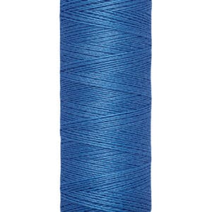 A spool of Gütermann blue sewing thread, wrapped around a beige cylindrical holder. The label reads "Gütermann" at the top and "100 m - 110 yds" at the bottom. The thread is neatly wound and vibrant blue in color.