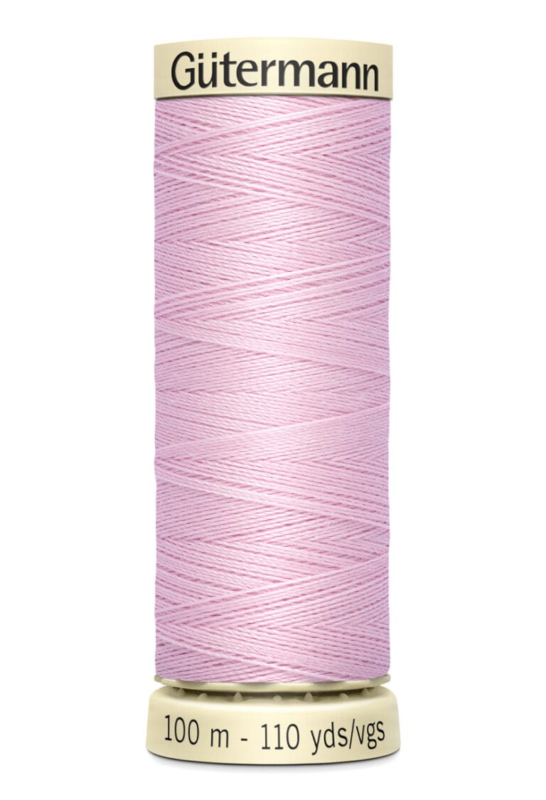 A spool of pale pink Gütermann sewing thread on a beige holder, labeled with "100 m - 110 yds/vgs".