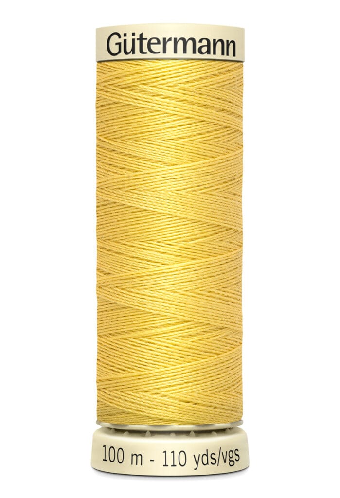 A spool of Gütermann sewing thread in light yellow is shown. The label indicates 100 meters or 110 yards. The spool is cylindrical with thread neatly wound around it.