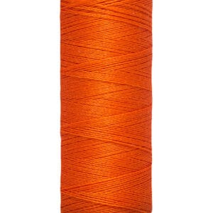 A spool of Gütermann orange sewing thread is shown, labeled with "100 m - 110 yds/vgs." The spool is off-white with the brand name printed at the top. The thread is tightly wound around the spool.