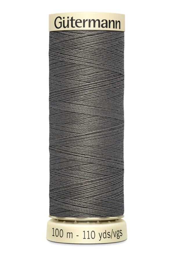 A spool of Gütermann thread in dark gray color, labeled with "100 m - 110 yds" at the bottom. The thread is neatly wound around a beige cylinder with the brand name displayed at the top.
