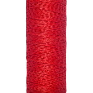 A spool of red Gütermann sewing thread, showing the brand name and measurements of 100 meters and 110 yards on the label. The thread is neatly wound around a light-colored spool.