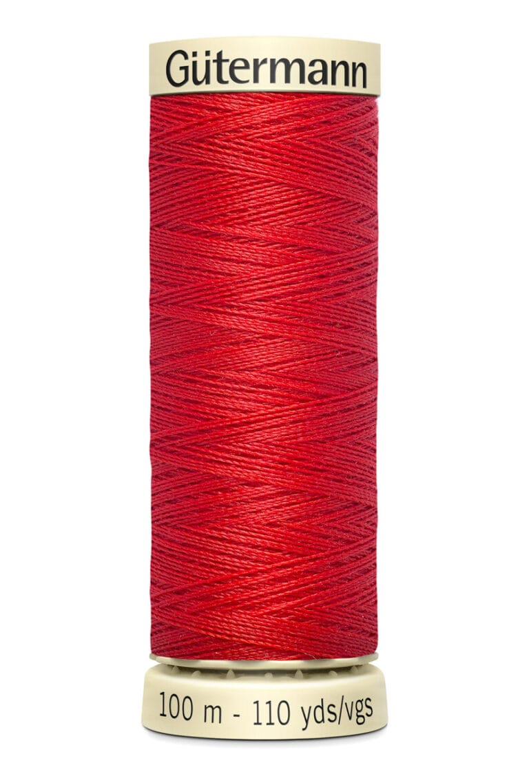 A spool of red Gütermann sewing thread, showing the brand name and measurements of 100 meters and 110 yards on the label. The thread is neatly wound around a light-colored spool.