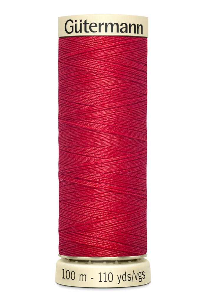 A spool of Gütermann red sewing thread stands upright. The label at the bottom indicates it contains 100 meters (110 yards) of thread.