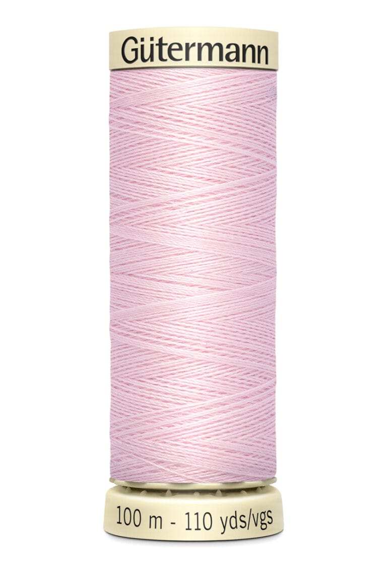 A spool of Gütermann pink sewing thread with a label indicating 100 meters (110 yards). The thread is neatly wound around a beige cylindrical holder.