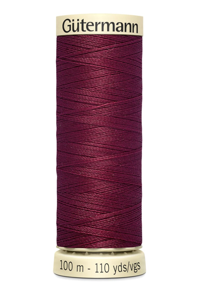 A spool of Gütermann sewing thread in a deep burgundy color. The label on top and bottom is cream-colored, featuring the brand name and measurement of 100 meters or 110 yards. The thread is neatly wound around the spool.