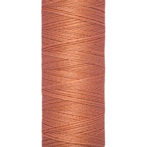 A spool of Gütermann thread in a soft terracotta color, labeled with "100 m - 110 yds" on the base.