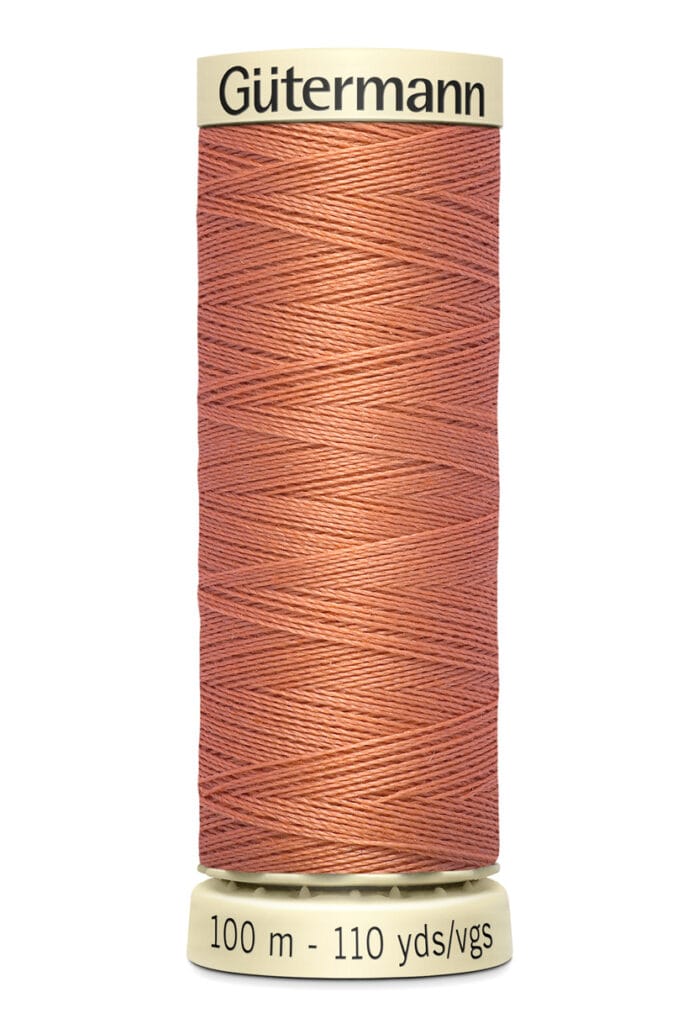 A spool of Gütermann thread in a soft terracotta color, labeled with "100 m - 110 yds" on the base.
