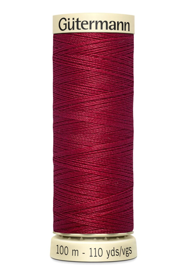 A spool of Gütermann thread, colored deep red, standing upright. The spool's label indicates it holds 100 meters or 110 yards of thread.