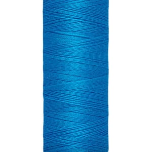 A spool of Gütermann blue sewing thread, with a label indicating 100 meters or 110 yards. The thread is wound tightly around a beige cylindrical spool.