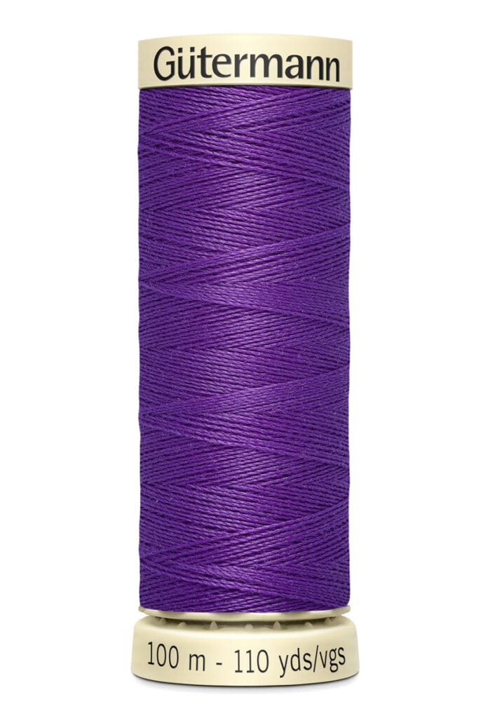 A spool of Gütermann thread with 100 meters (110 yards) of vibrant purple thread. The spool is beige with brand and measurement details printed on it.