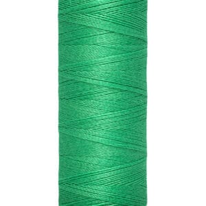 A spool of green Gütermann sewing thread, labeled with "100 m - 110 yds/vgs," is wound neatly around a beige core.