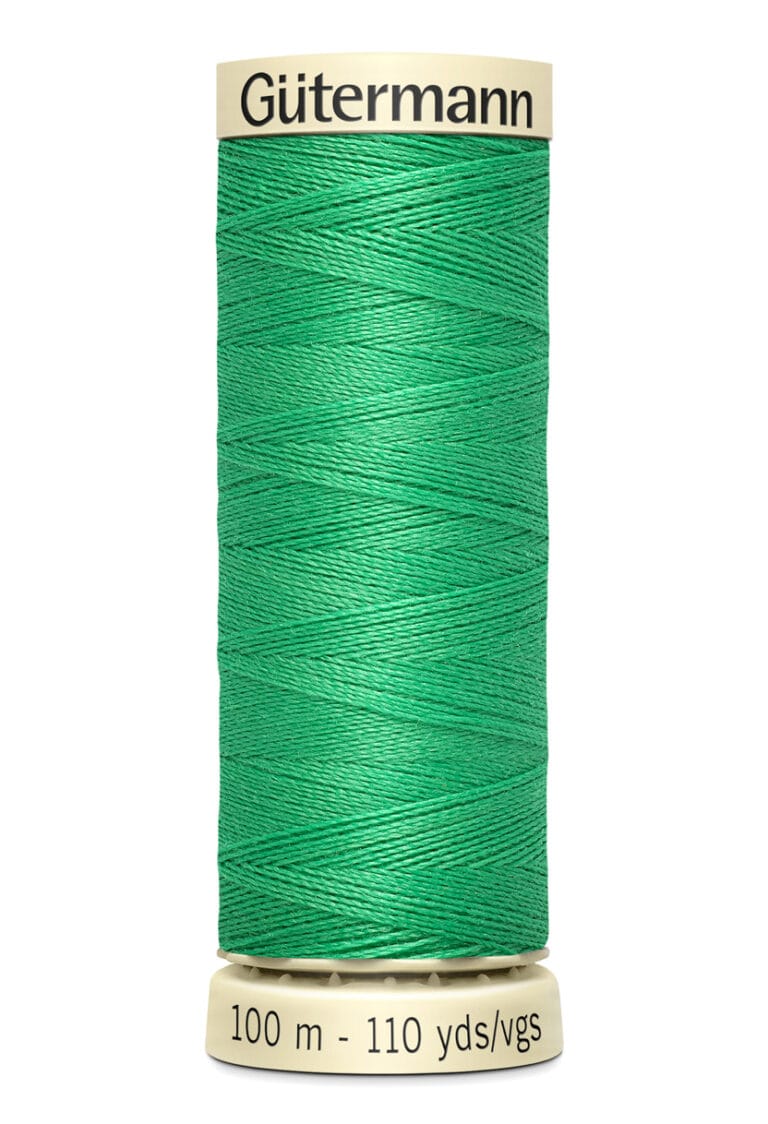 A spool of green Gütermann sewing thread, labeled with "100 m - 110 yds/vgs," is wound neatly around a beige core.