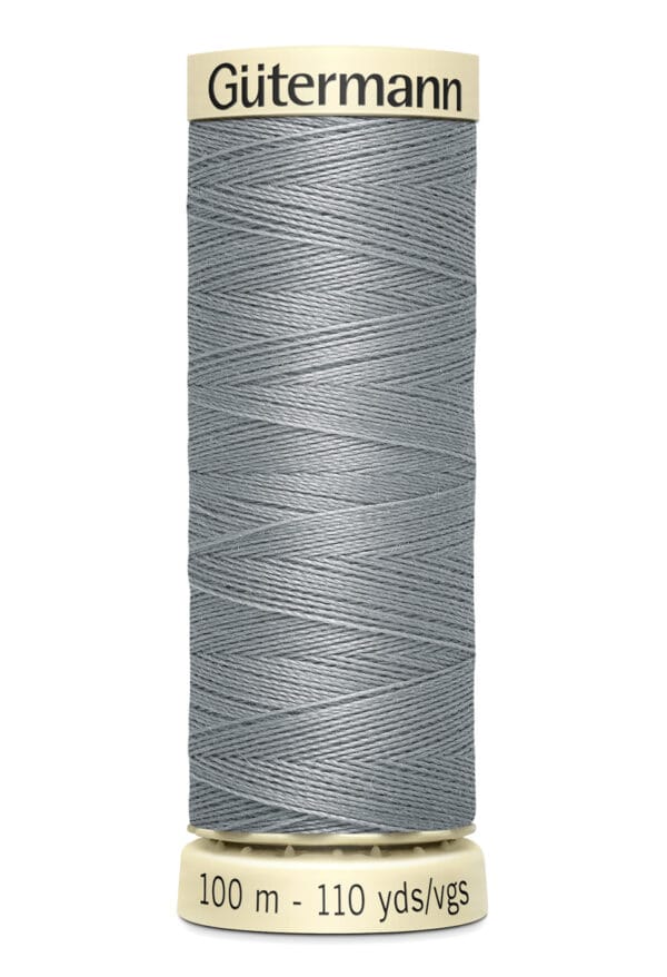 A spool of Gütermann gray sewing thread, labeled as 100 meters (110 yards). The thread is tightly wound around a beige spool with black text.