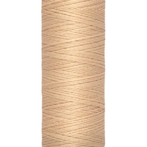A spool of Gütermann beige sewing thread, labeled with "100 m - 110 yds," featuring tightly wound thread on a cylindrical holder.