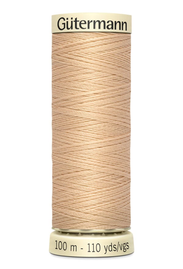 A spool of Gütermann beige sewing thread, labeled with "100 m - 110 yds," featuring tightly wound thread on a cylindrical holder.