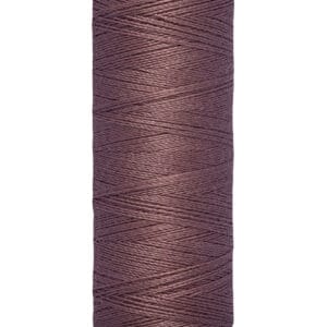 Spool of Gütermann thread in a dusty rose color, labeled "100 m - 110 yds." The spool features cream-colored ends with "Gütermann" printed on top.