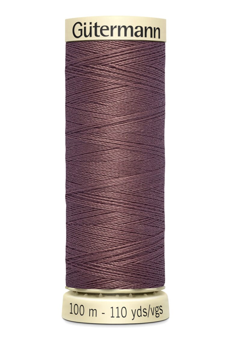 Spool of Gütermann thread in a dusty rose color, labeled "100 m - 110 yds." The spool features cream-colored ends with "Gütermann" printed on top.