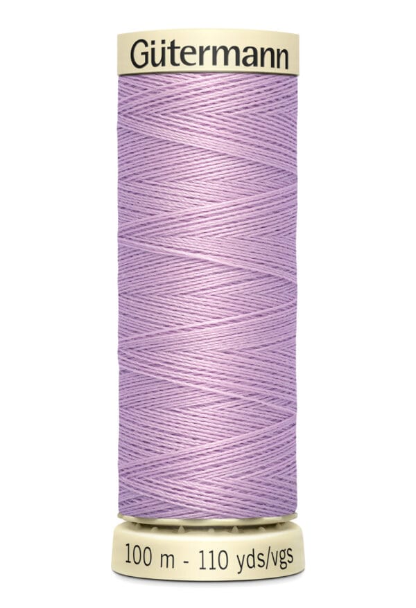 A spool of Gütermann thread in light purple. The spool is cylindrical, with a beige top and bottom featuring the brand name and measurements of 100 meters and 110 yards. The thread is neatly wound around the spool.