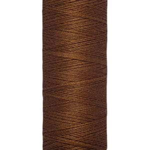 A spool of Gütermann brown sewing thread, labeled with "100 m - 110 yds" on the bottom and "Gütermann" on the top. The thread is tightly wound around a cream-colored spool.