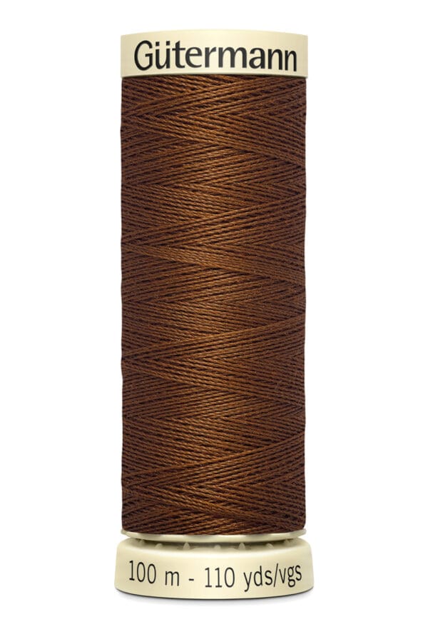 A spool of Gütermann brown sewing thread, labeled with "100 m - 110 yds" on the bottom and "Gütermann" on the top. The thread is tightly wound around a cream-colored spool.