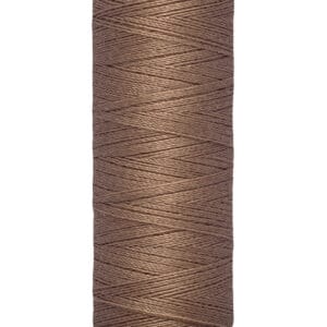 A spool of brown Gütermann sewing thread with a label indicating 100 meters or 110 yards. The spool is beige at the top and bottom, and the thread is tightly wound around it.
