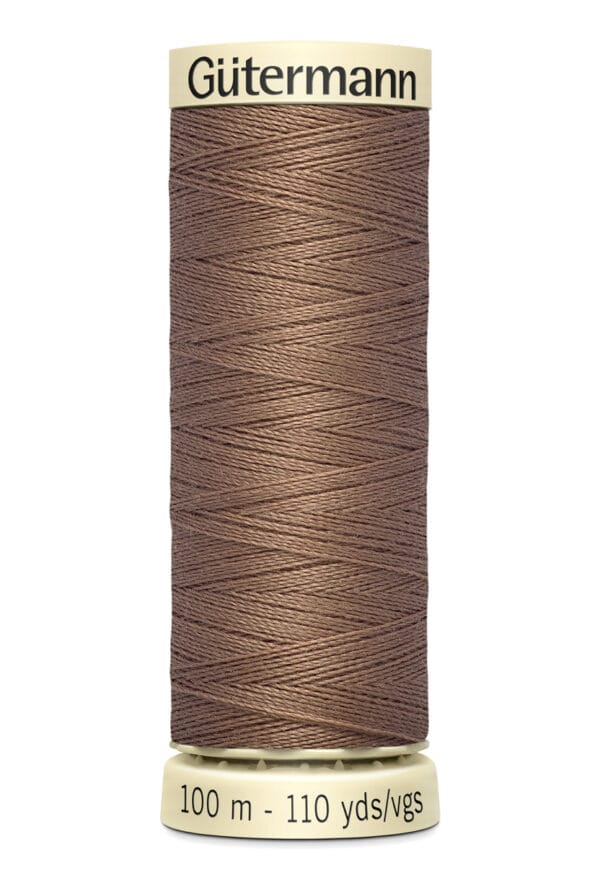 A spool of brown Gütermann sewing thread with a label indicating 100 meters or 110 yards. The spool is beige at the top and bottom, and the thread is tightly wound around it.