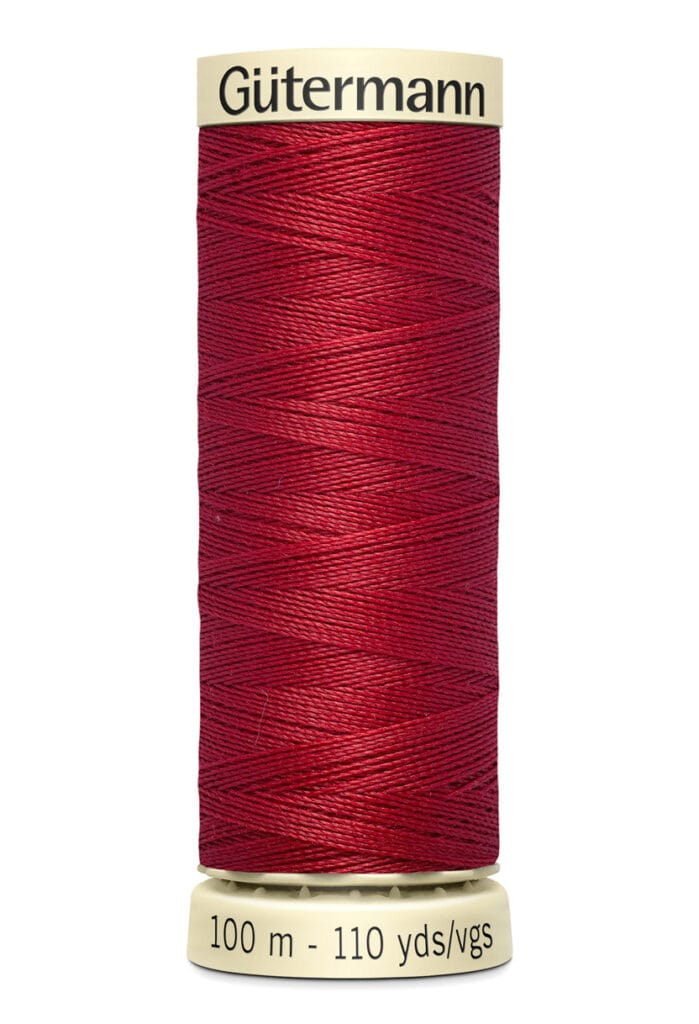 A spool of Gütermann red thread with 100 meters or 110 yards of material. The spool has a cream-colored top and bottom with black text stating the brand and length.
